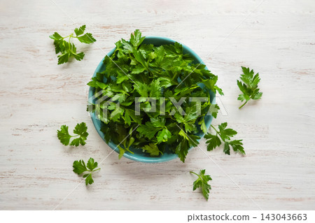 Top view of fresh green parsley in a ceramic bowl on white wooden background Top view of fresh green parsley in a ceramic bowl on white wooden background 143043663