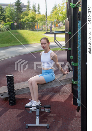 Caucasian woman on incline bench for abdominal muscles at sports ground. Caucasian woman on incline bench for abdominal muscles at sports ground. 143043704