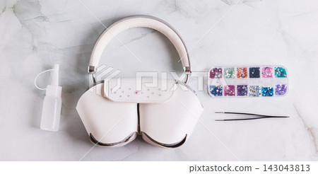 The process of decorating a headphone case with colorful rhinestones on a table top view web banner The process of decorating a headphone case with colorful rhinestones on a table top view web banner 143043813