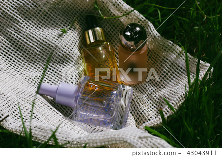 Natural skincare serum bottles on linen fabric and fresh green grass, clean beauty cosmetics with botanical wellness aesthetic, sustainable self care. 143043911