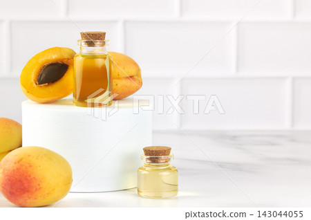 Apricot oil in glass bottles with fresh apricots on white background. Natural skincare, aromatherapy concept. Copy space Apricot oil in glass bottles with fresh apricots on white background. Natural skincare, aromatherapy concept. Copy space 143044055