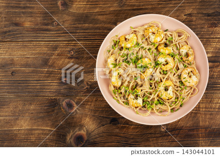 Creamy shrimp spaghetti served on plate with chopped chives. Creamy shrimp spaghetti served on plate with chopped chives. 143044101