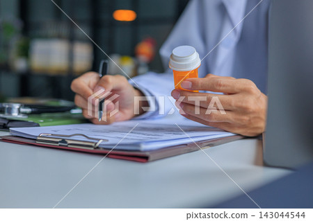 Physician managing medication and writing prescriptions order for patient Physician managing medication and writing prescriptions order for patient 143044544