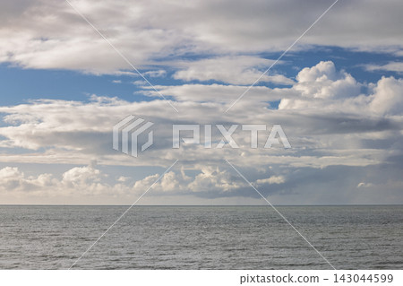 Expansive Horizon with Dynamic Cloudscape Over Calm Sea Water, Serene Sky Reflecting Light Above Peaceful Seascape View. Ostend town in Belgium, Europe. Expansive Horizon with Dynamic Cloudscape Over Calm Sea Water, Serene Sky Reflecting Light Above Peaceful Seascape View. Ostend town in Belgium, Europe. 143044599