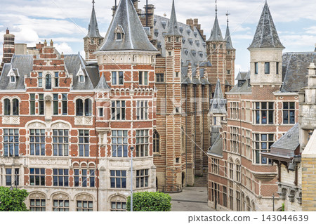 Antwerp town in Belgium, Europe. Historic European Architecture Featuring Red Brick Buildings, Elaborate Turrets, and Ornate Facades Under a Cloudy Sky Antwerp town in Belgium, Europe. Historic European Architecture Featuring Red Brick Buildings, Elaborate Turrets, and Ornate Facades Under a Cloudy Sky 143044639