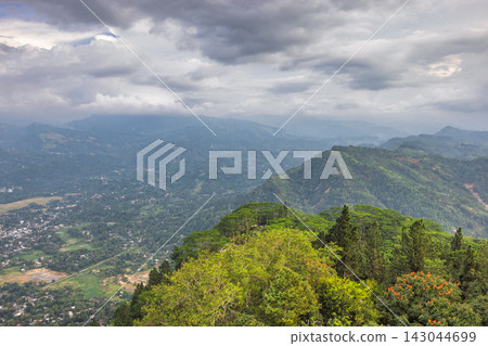 View from Ambuluwawa Tower, multi-religious temple complex located in Gampola, in Sri Lanka. Dramatic Sky Over Lush Green Mountains and Valley, Village Nestled in Nature's Embrace 143044699