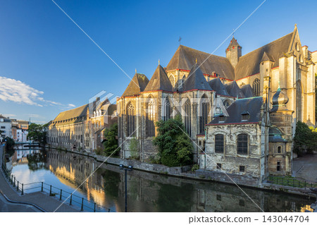 Ghent town in Belgium, Europe. Saint Michael's Church, Historic European Cityscape with Grand Architectural Landmark Reflecting in Calm Canal Water on a Sunny Day Ghent town in Belgium, Europe. Saint Michael's Church, Historic European Cityscape with Grand Architectural Landmark Reflecting in Calm Canal Water on a Sunny Day 143044704