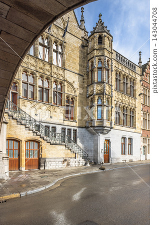 Ghent town in Belgium, Europe. Historic European stone building with ornate architecture, bay window, and arched entrance framing on a cobblestone street under a clear sky Ghent town in Belgium, Europe. Historic European stone building with ornate architecture, bay window, and arched entrance framing on a cobblestone street under a clear sky 143044708