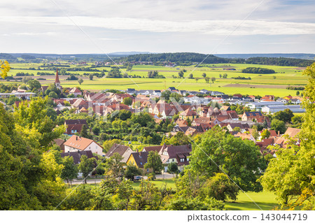 Colmberg, historic small town in region of Bavaria in Germany, Europe. Panoramic view of a charming European village nestled in a lush green valley under a partly cloudy sky Colmberg, historic small town in region of Bavaria in Germany, Europe. Panoramic view of a charming European village nestled in a lush green valley under a partly cloudy sky 143044719