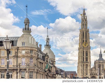 Antwerp town in Belgium, Europe. Historic European Cityscape with Grand Architectural Buildings and Soaring Gothic Tower under a Bright Blue Sky with Clouds 143044729