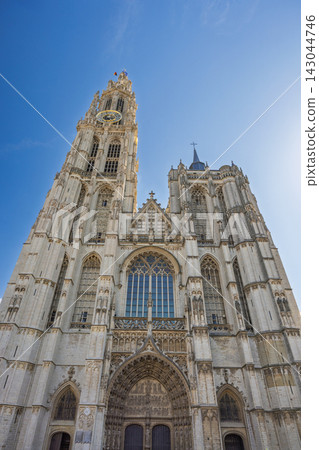 Antwerp town in Belgium, Europe. Cathedral of Our Lady, Majestic European Cathedral Tower and Ornate Facade Against a Clear Blue Sky on a Bright, Sunny Day, Low Angle View Antwerp town in Belgium, Europe. Cathedral of Our Lady, Majestic European Cathedral Tower and Ornate Facade Against a Clear Blue Sky on a Bright, Sunny Day, Low Angle View 143044746