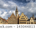 Ghent town in Belgium, Europe. Historic European Architecture Under Dramatic Sky: A Collection of Ornate Gabled Buildings and a Prominent Clock Tower 143044813