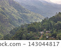 Verdant Mountain Landscape with Lush Forest and Secluded Village Architecture Nestled in Rolling Hillsides. Mountain landscape near Ella in Sri Lanka. 143044817