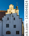 Rothenburg ob der Tauber, medieval old town in region of Bavaria in Germany, Europe. Historic White Facade with Gabled Roof and Ornate Tower Against Blue Sky 143044824