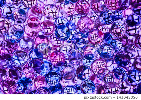 Transparent glass or gel balls with reflection of mesh grid inside each ball, illuminated in blue-violet-pink color scheme Transparent glass or gel balls with reflection of mesh grid inside each ball, illuminated in blue-violet-pink color scheme 143045056