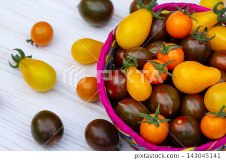 Colorful organic cherry tomatoes on the white wooden table. Colorful organic cherry tomatoes on the white wooden table. 143045141