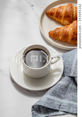 Cup of freshly espresso coffee and fresh croissants on a marble background Cup of freshly espresso coffee and fresh croissants on a marble background 143045182