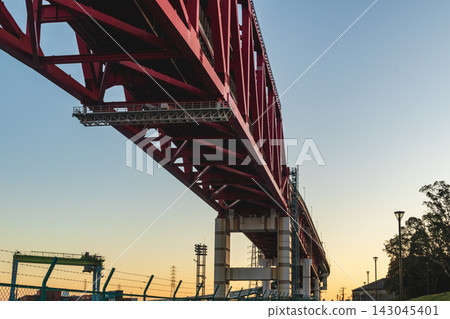 A powerful framework of a large red bridge viewed from below at sunset. A powerful framework of a large red bridge viewed from below at sunset. 143045401