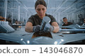 Focused Woman Technician Connecting Electronic Components to Drone Fuselage 143046870
