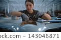 Woman Assembling Drone in Modern Factory with Colleague Working on Production Line 143046871