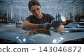 Woman Assembling Drone in Modern Factory with Colleague Working on Production Line 143046872