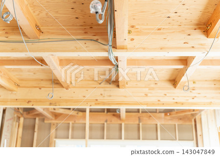 這是一個正在建造新木屋的建築工地。由於房屋仍在施工中,可以看到橫樑、天花板框架和電線。 這是一個正在建造新木屋的建築工地。由於房屋仍在施工中,可以看到橫樑、天花板框架和電線。 143047849