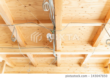 這是一個正在建造新木屋的建築工地。由於房屋仍在施工中,可以看到橫樑、天花板框架和電線。 這是一個正在建造新木屋的建築工地。由於房屋仍在施工中,可以看到橫樑、天花板框架和電線。 143047850