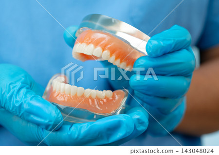 Denture, dentist holding dental teeth model to study and treat in hospital. Denture, dentist holding dental teeth model to study and treat in hospital. 143048024