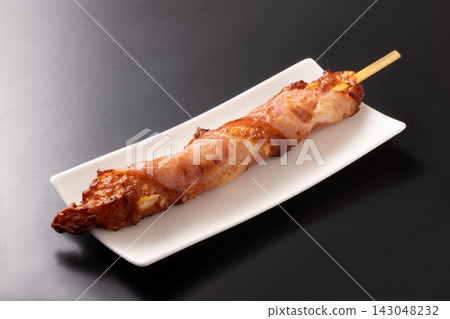 Cheese-filled fish cake wrapped in bacon, on a skewer. Cheese-filled fish cake wrapped in bacon, on a skewer. 143048232