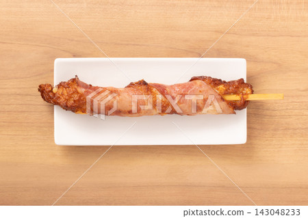 Cheese-filled fish cake wrapped in bacon, on a skewer. Cheese-filled fish cake wrapped in bacon, on a skewer. 143048233
