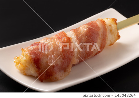 Fish cake wrapped in bacon on a skewer Fish cake wrapped in bacon on a skewer 143048264