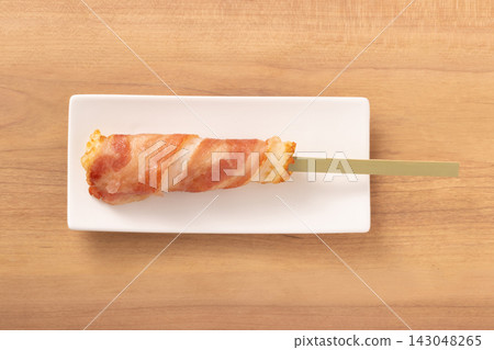 Fish cake wrapped in bacon on a skewer Fish cake wrapped in bacon on a skewer 143048265