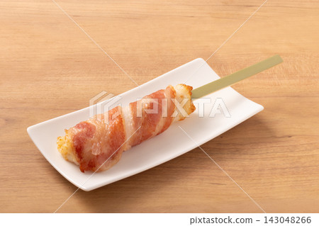 Fish cake wrapped in bacon on a skewer Fish cake wrapped in bacon on a skewer 143048266