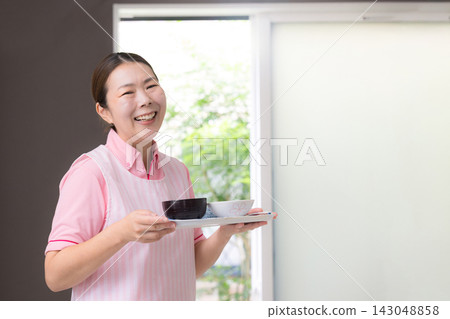 這張圖片描繪了女性工作人員提供餐食,這是家政服務的一部分,包括家庭護理、家庭幫手以及提供日常生活、烹飪和膳食準備方面幫助的人員。 這張圖片描繪了女性工作人員提供餐食,這是家政服務的一部分,包括家庭護理、家庭幫手以及提供日常生活、烹飪和膳食準備方面幫助的人員。 143048858