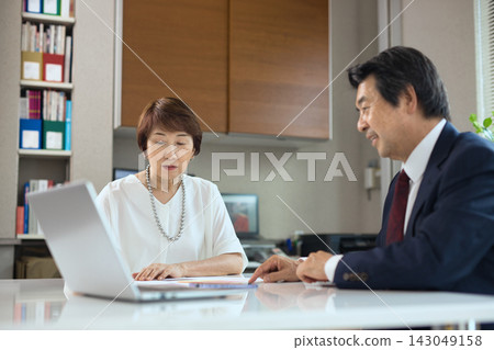 一對六十多歲的商人夫婦在辦公室開會。 一對六十多歲的商人夫婦在辦公室開會。 143049158