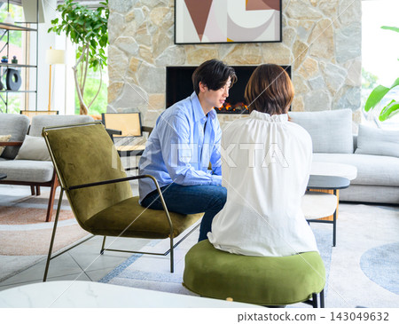 A man and a woman facing each other indoors, having a conversation. A man and a woman facing each other indoors, having a conversation. 143049632