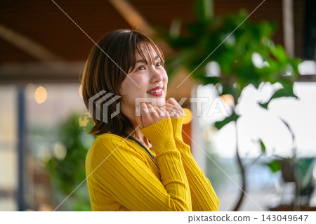 一位身穿黃色洋裝的女子麵帶微笑。 143049647