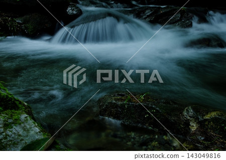 A clear stream flows over moss-covered rock faces, creating a beautiful waterfall and flowing water (Fubu River, Yorii Town, Saitama Prefecture). A clear stream flows over moss-covered rock faces, creating a beautiful waterfall and flowing water (Fubu River, Yorii Town, Saitama Prefecture). 143049816