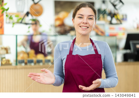 Female cafe employee greets guests of establishment Female cafe employee greets guests of establishment 143049841