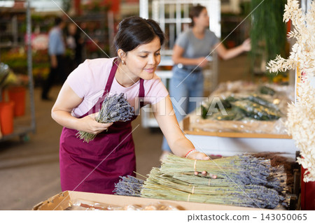 Girl florist chooses fresh lavender to make flower bouquet at flower market Girl florist chooses fresh lavender to make flower bouquet at flower market 143050065
