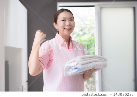 女員工正在洗衣服,這是家事服務、家庭照護、家庭幫手、維生設備的一部分,她手裡拿著洗好的衣服,擺出勝利的姿勢。 女員工正在洗衣服,這是家事服務、家庭照護、家庭幫手、維生設備的一部分,她手裡拿著洗好的衣服,擺出勝利的姿勢。 143050253