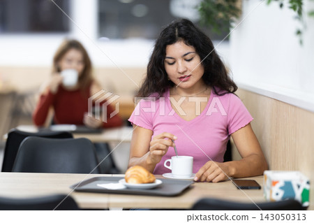 Attractive female sitting alone at table in cozy cafe, drinking fragrant coffee 143050313