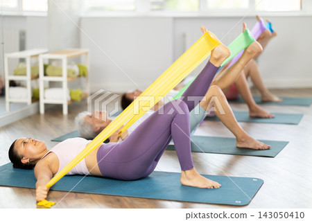 Asian woman exercising with elastic band at group training Asian woman exercising with elastic band at group training 143050410