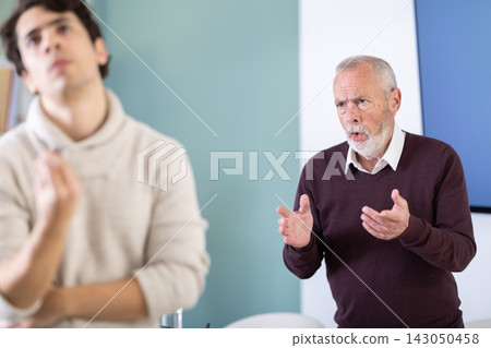 Elderly man scolds young man in office Elderly man scolds young man in office 143050458