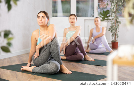 European women practice the Ardha Matsyendrasana pose European women practice the Ardha Matsyendrasana pose 143050474