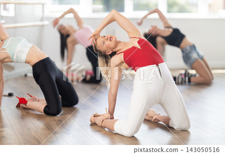 Fit woman in high heels practicing vogue dance on floor in studio 143050516