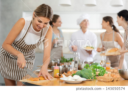Young woman cutting raw chicken breast Young woman cutting raw chicken breast 143050574