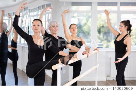 Adult woman teacher correcting female dancers Adult woman teacher correcting female dancers 143050609