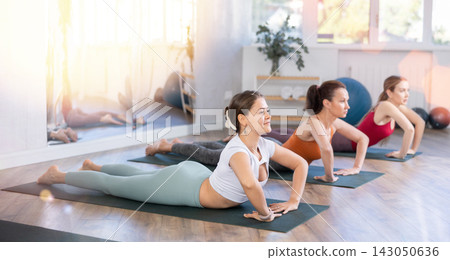 Young women yoga performing bow pose variation on rug Young women yoga performing bow pose variation on rug 143050636