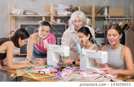 Group of busy women sewing and drawing with teacher at dressmaking courses Group of busy women sewing and drawing with teacher at dressmaking courses 143050655